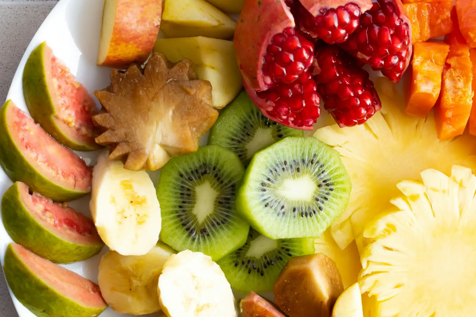 Đĩa trái cây nhiệt đới với kiwi, dứa, ổi và lựu cho bữa sáng