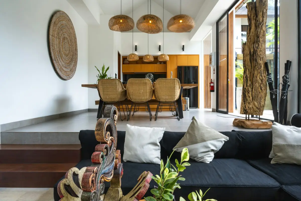Phòng khách villa với sofa trắng, bàn ăn gỗ và cửa kính mở ra sân hiên